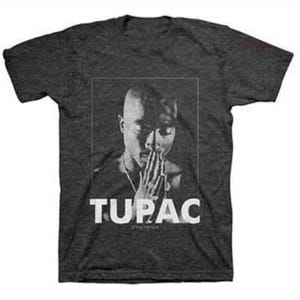 May include: A dark heather grey t-shirt with a black and white image of rapper Tupac Shakur. The image shows Tupac with his hands clasped in prayer. The text "TUPAC" is printed in white below the image.