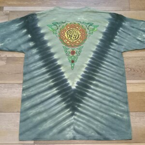 Puede incluir: Camiseta te&ntilde;ida con tinte anudado en tonos azules y verdes, con un dise&ntilde;o central con las palabras "Grateful Dead" en un patr&oacute;n circular. La parte posterior de la camiseta tiene un patr&oacute;n de te&ntilde;ido anudado en forma de V.