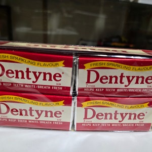 May include: A pack of four Dentyne gum packages. Each package is red and white with the text "Fresh Sparkling Flavor" and "Dentyne" in yellow. The text "7 Sticks" and "Helps Keep Teeth White/Breath Fresh" is also printed on each package.
