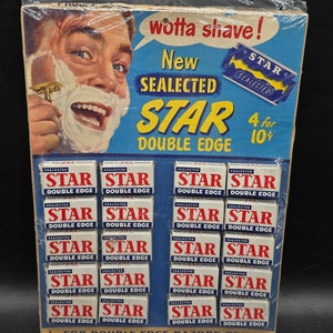 May include: A vintage box of Star Double Edge razor blades. The box is blue and white and features a man shaving with a razor. The text on the box reads "wotta shave!" "New SEALECTED STAR DOUBLE EDGE" "4 for 10¢" and "FOR DOUBLE EDGE RAZORS ONLY".