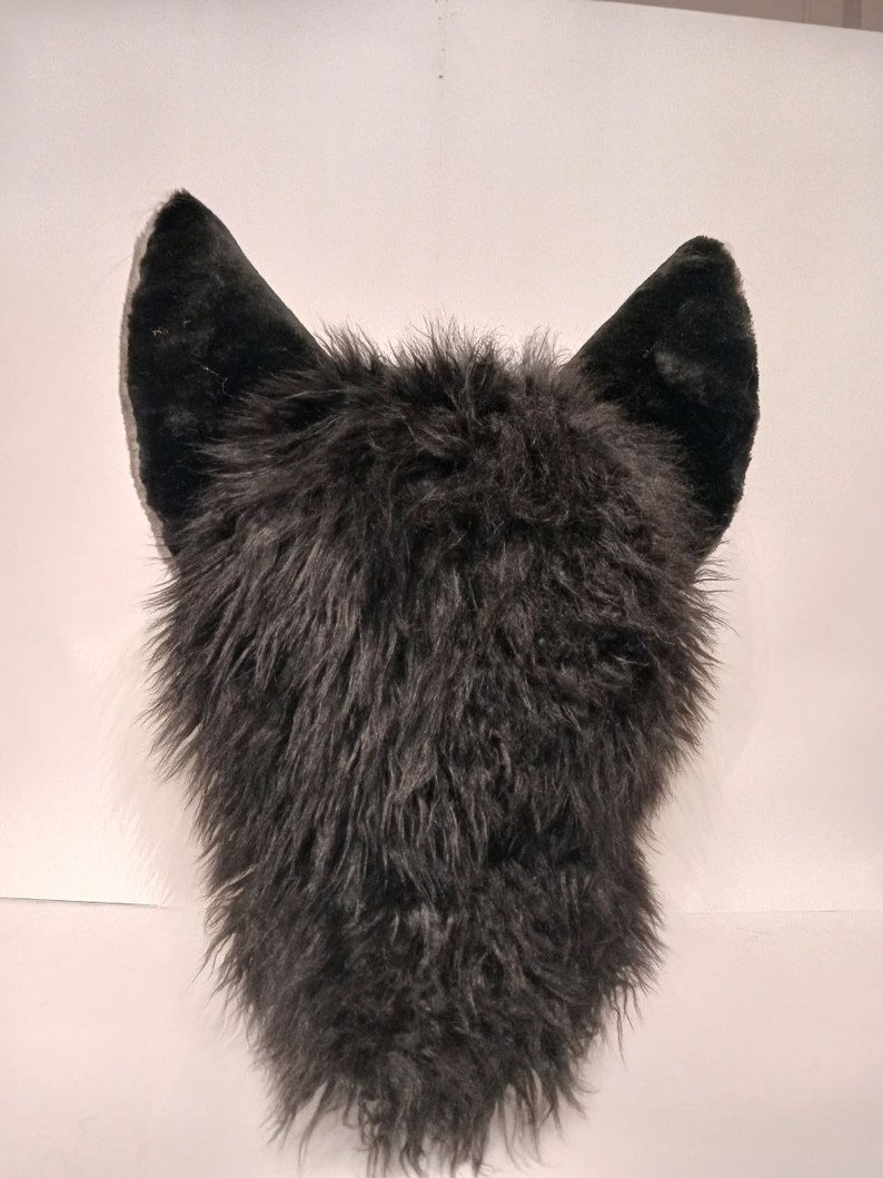 May include: Black furry wolf head with large, black ears. The fur is soft and fluffy.