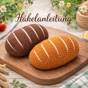 May include: Two crocheted bread loaves, one brown and one orange, rest on a wooden cutting board. White stripes adorn the top of each loaf. The German text "Häkelanleitung" is visible. The scene includes tomatoes, butter, honey, and decorative flowers.