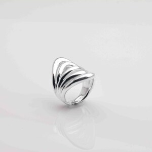 May include: A silver ring with a unique design featuring multiple overlapping curved bands.
