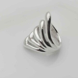 May include: A silver ring with a unique, abstract design featuring multiple curved lines that create a wave-like pattern.