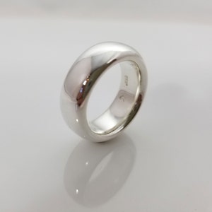 May include: A silver band ring with a smooth, rounded surface. The ring is marked with "925" on the inside.
