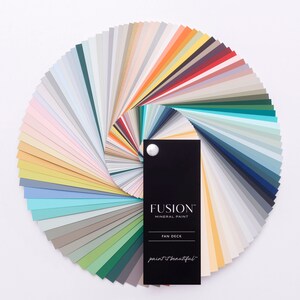 May include: A color fan deck featuring a variety of paint colors from Fusion Mineral Paint. The fan deck is open and shows a wide range of colors, including blues, greens, yellows, and neutrals. The fan deck is labeled "Fusion Mineral Paint" and "Fan Deck".