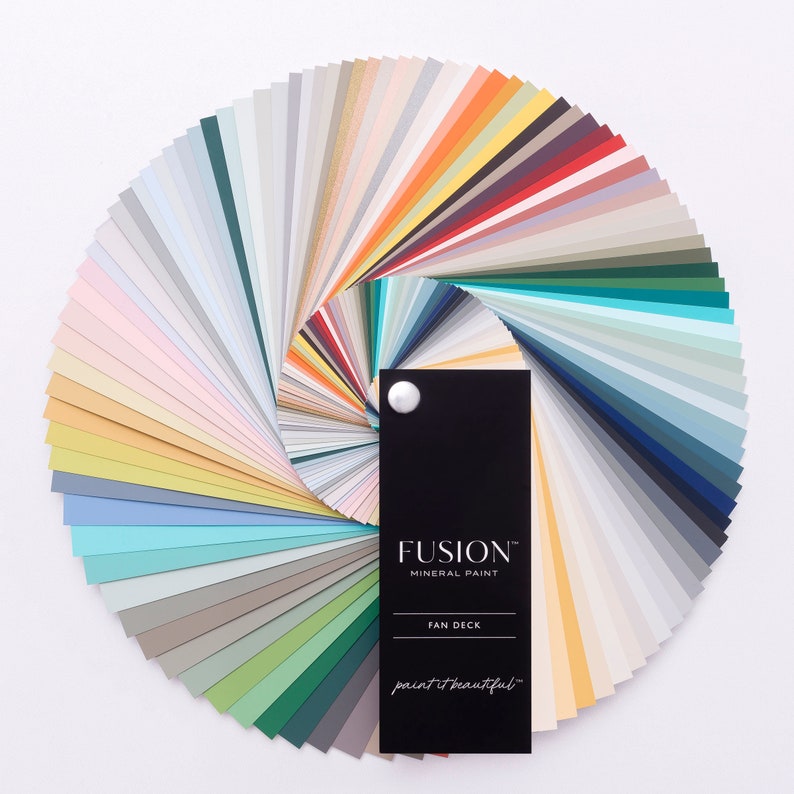 May include: A color fan deck featuring a variety of paint colors from Fusion Mineral Paint. The fan deck is open and shows a wide range of colors, including blues, greens, yellows, and neutrals. The fan deck is labeled "Fusion Mineral Paint" and "Fan Deck".