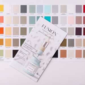 May include: A color chart for Fusion Mineral Paint, showing a variety of colors in small squares. The chart includes a paintbrush and a bottle of paint. The text on the chart reads "Fusion Mineral Paint, paint it beautiful." and "Built-in top coat, easy to apply, excellent coverage."