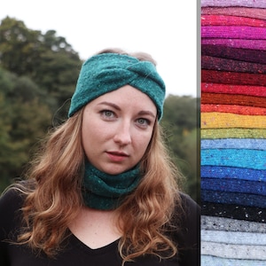 Könnte beinhalten: Ein türkisfarbenes gestricktes Stirnband mit einem gedrehten Knotendesign. Das Stirnband wird von einer Person mit langen, welligen, hellbraunen Haaren getragen. Das Stirnband ist vor einem verschwommenen Hintergrund aus grünen Bäumen zu sehen.