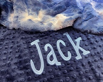 May include: A soft blue and white baby blanket with the name "Jack" embroidered in white on the blue side.
