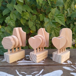 May include: Three wooden tree sculptures with different designs. One has a rounded tree shape, another features heart-shaped leaves, and the third has a more abstract form. Each is mounted on a rectangular base.