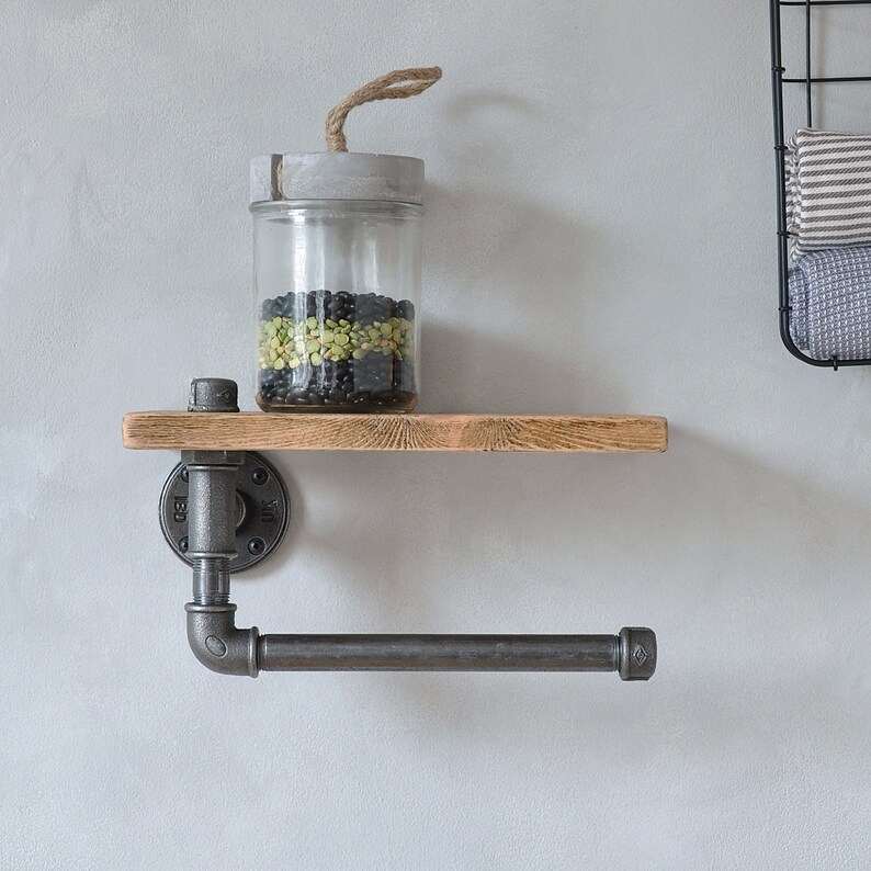 May include: A rustic wooden shelf with a black metal pipe frame and a black metal towel bar. A glass jar with a concrete lid and a rope handle sits on the shelf, filled with black and green beans.