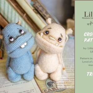 Może przedstawiać: Wzór na szydełku do amigurumi trolla. Wzór jest dostępny w formacie PDF i jest uważany za średnio trudny. Obraz przedstawia dwa gotowe trolle, jeden niebieski, a drugi beżowy.