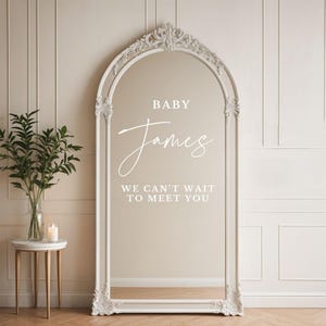 May include: White ornate mirror with the text "BABY James WE CAN'T WAIT TO MEET YOU" on the glass.