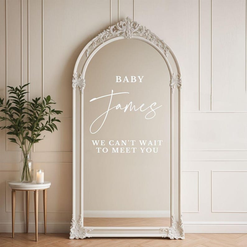 May include: White ornate mirror with the text "BABY James WE CAN'T WAIT TO MEET YOU" on the glass.