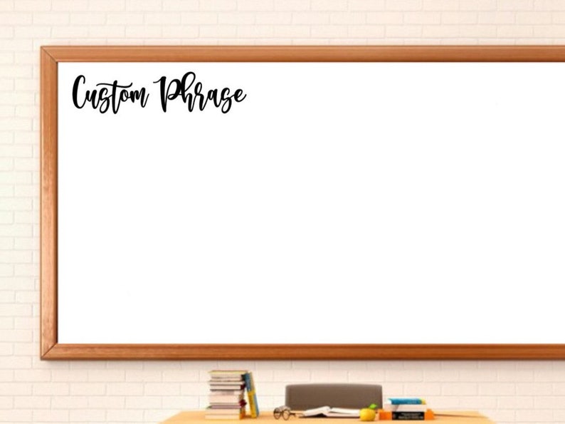 May include: A rectangular white dry-erase board with a light brown wooden frame. The board features the black cursive text Custom Phrase in the upper left corner. The surface is smooth and blank, providing a large area for writing notes.