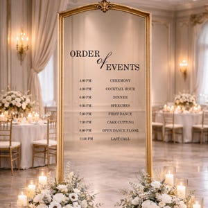 Pode incluir: Um espelho alto e retangular com moldura dourada apresentando o texto preto ORDER OF EVENTS, seguido por uma programa&ccedil;&atilde;o das 16h00 CEREMONY &agrave;s 23h30 LAST CALL. O espelho &eacute; decorado com arranjos florais brancos na base.