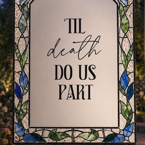 May include: A rectangular sign with a white center panel featuring the black text 'TIL death DO US PART'. The sign is framed by a decorative border of stained glass in shades of blue and green, set within a black metal frame with a scrollwork top.