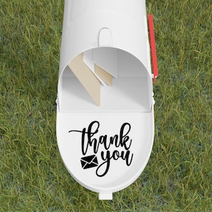 May include: White mailbox with a black vinyl decal that says "thank you" with a small envelope icon. The mailbox is open and has a red flag.