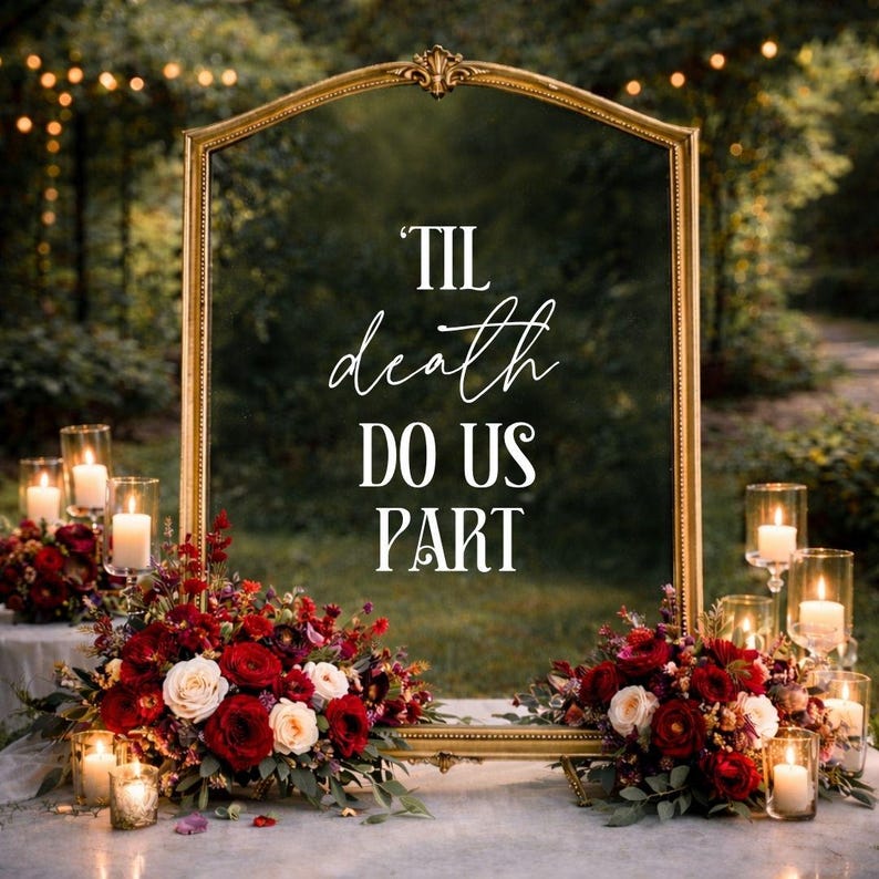 May include: A large, arched gold-framed mirror featuring the white text 'TIL death DO US PART' centered on the glass. The mirror is decorated with arrangements of deep red and white roses, greenery, and several small glass candle holders with lit candles.