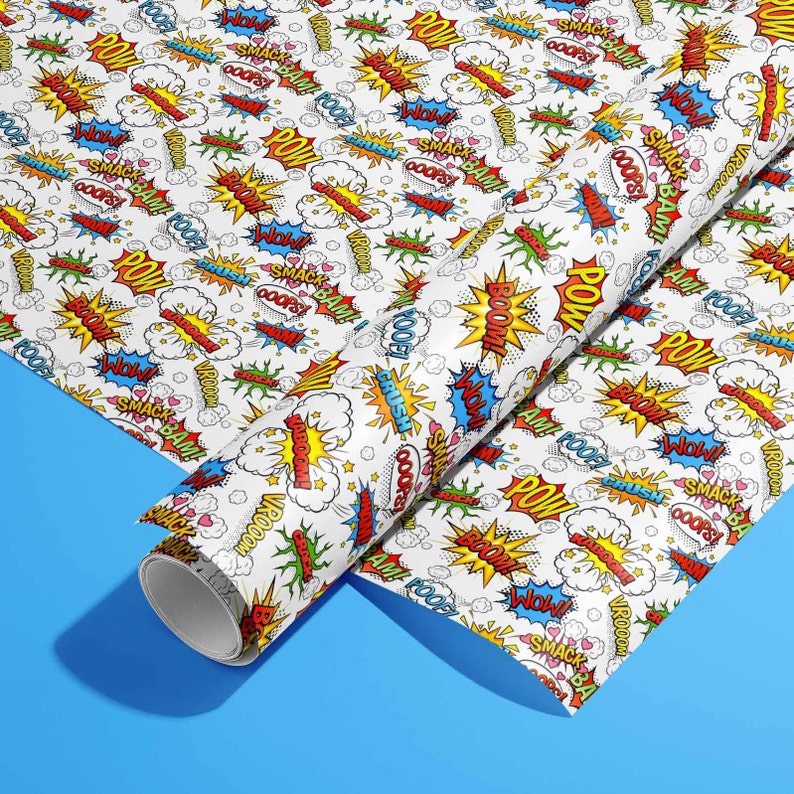 Op de afbeelding: Wit inpakpapier met een herhalend patroon van kleurrijke stripboek-spraakballonnen met woorden als "POW", "BOOM", "SMACK BAM" en "VROOOM!"