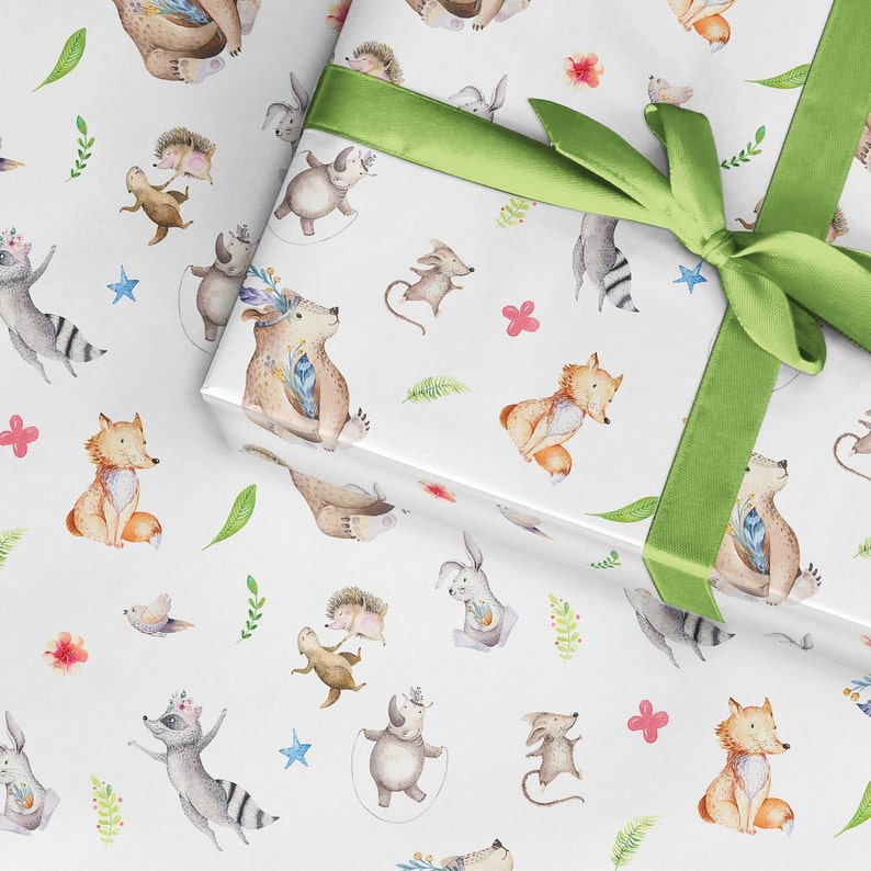 May include: White wrapping paper with a repeating pattern of watercolor illustrations of woodland animals, including foxes, raccoons, bears, and hedgehogs. The animals are depicted in various poses, some jumping, some sitting, and some standing. The paper is decorated with green leaves, pink flowers, and blue stars.