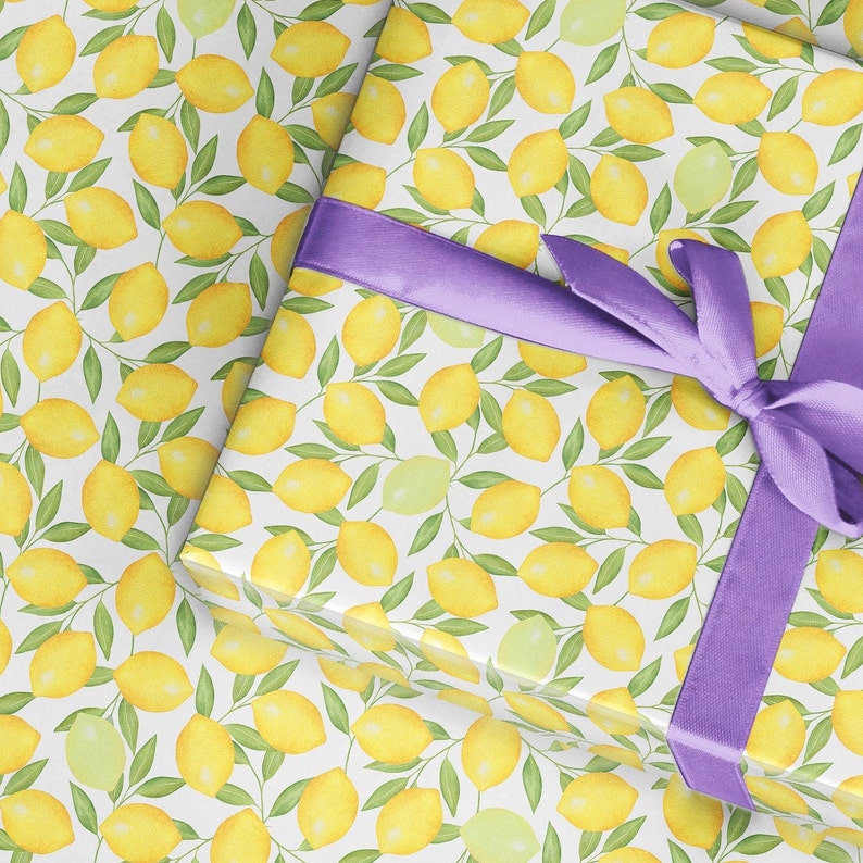 May include: White gift wrap with a repeating pattern of yellow lemons and green leaves. A purple ribbon is tied around the gift wrap.