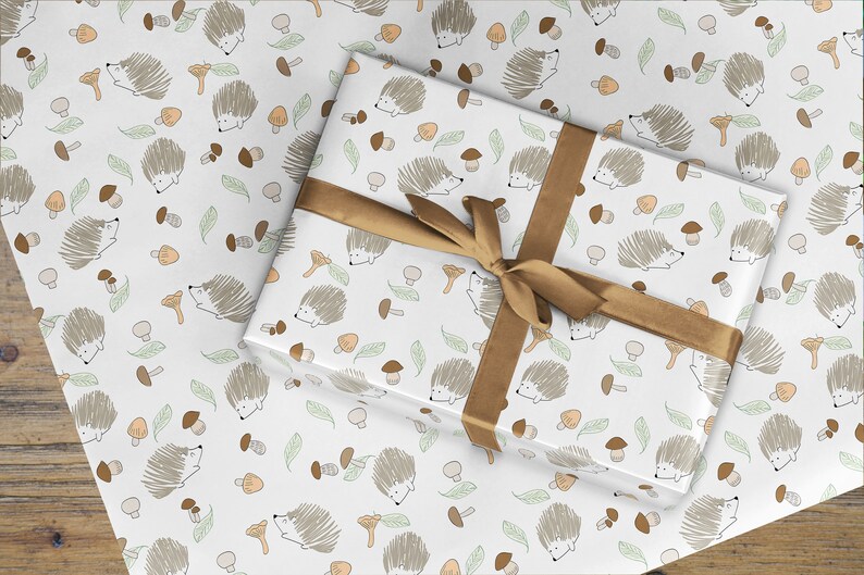 May include: White gift wrap with a repeating pattern of brown hedgehogs, green leaves, and brown mushrooms. The gift wrap is tied with a brown ribbon.