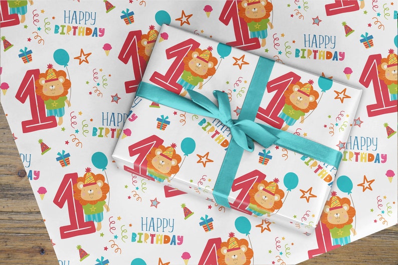 May include: White wrapping paper with a repeating pattern of a red number one, a cartoon lion wearing a party hat, stars, balloons, and the text "Happy Birthday".