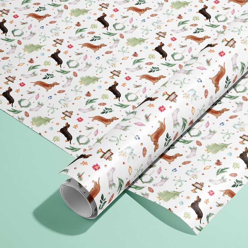 Peut inclure: Papier d'emballage blanc avec un motif r&eacute;p&eacute;titif de chiens teckels bruns et noirs, de houx, de gui et d'autres &eacute;l&eacute;ments de No&euml;l.