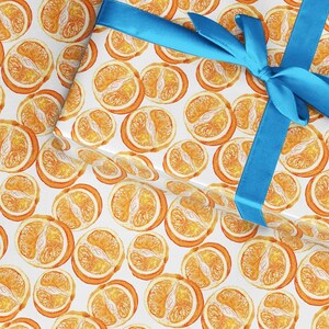 May include: White wrapping paper with a repeating pattern of orange slices. A blue ribbon is tied in a bow on top of the paper.
