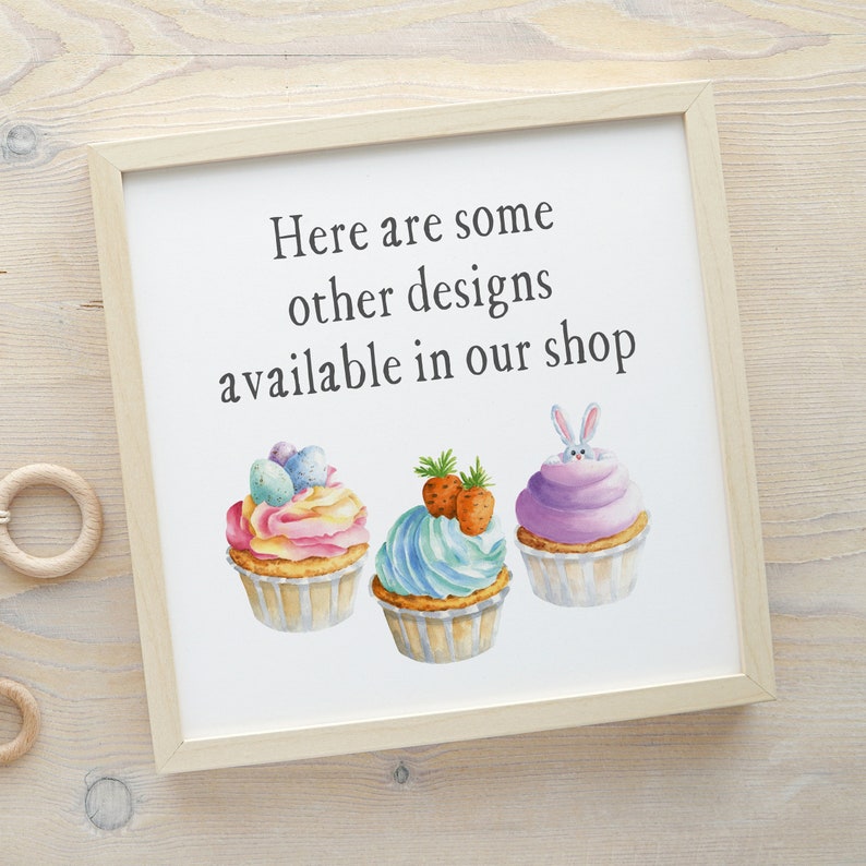 May include: A white framed sign with the text "Here are some other designs available in our shop" and three watercolor illustrations of cupcakes. The cupcakes are decorated with pastel colors, sprinkles, and Easter-themed decorations like eggs and a bunny.