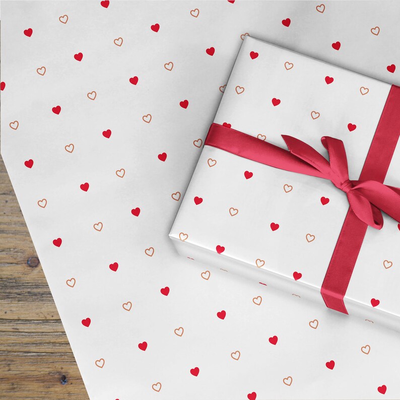 May include: White gift wrap with a red ribbon and a repeating pattern of small red and copper hearts.