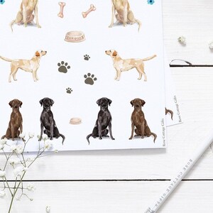 May include: A sheet of stickers featuring illustrations of Labrador Retriever dogs in various poses. The stickers are on a white background and include paw prints, bones, and a dog food bowl.