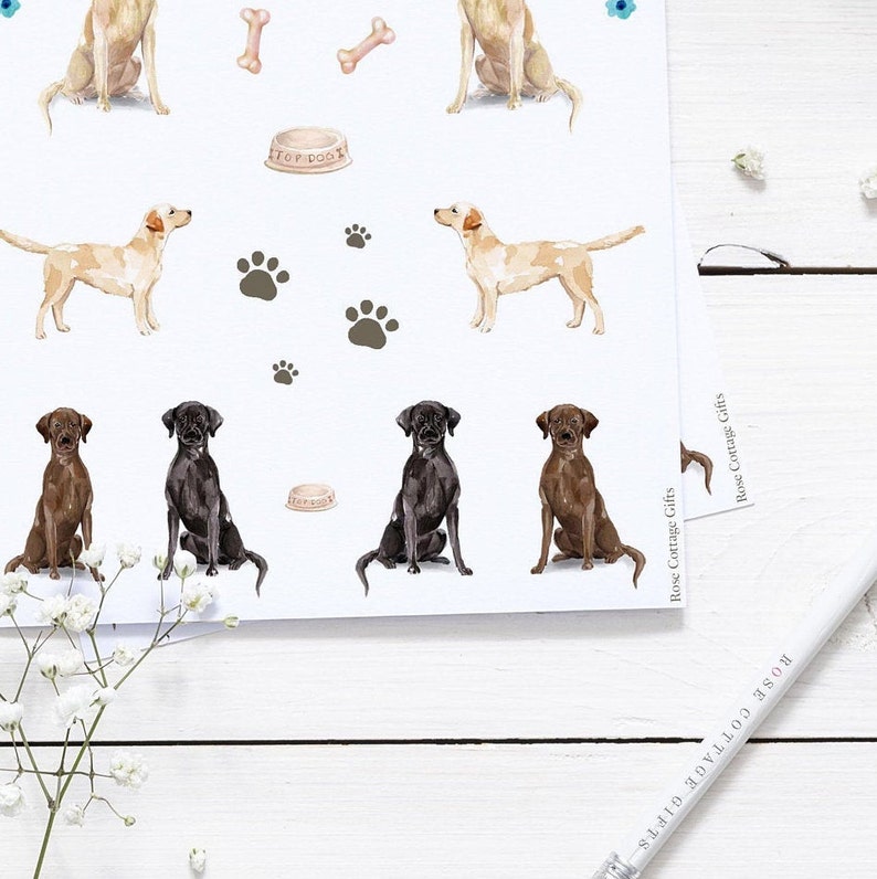 May include: A sheet of stickers featuring illustrations of Labrador Retriever dogs in various poses. The stickers are on a white background and include paw prints, bones, and a dog food bowl.