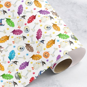May include: White wrapping paper with a Halloween theme. The paper features a repeating pattern of ghosts, pumpkins, bats, bones, stars, and leaves in various colors, including orange, green, purple, and yellow.