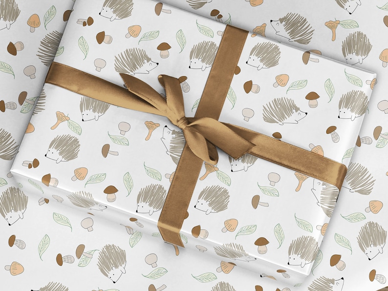 May include: White wrapping paper with a repeating pattern of brown hedgehogs, mushrooms, and leaves. A brown ribbon is tied around the paper.