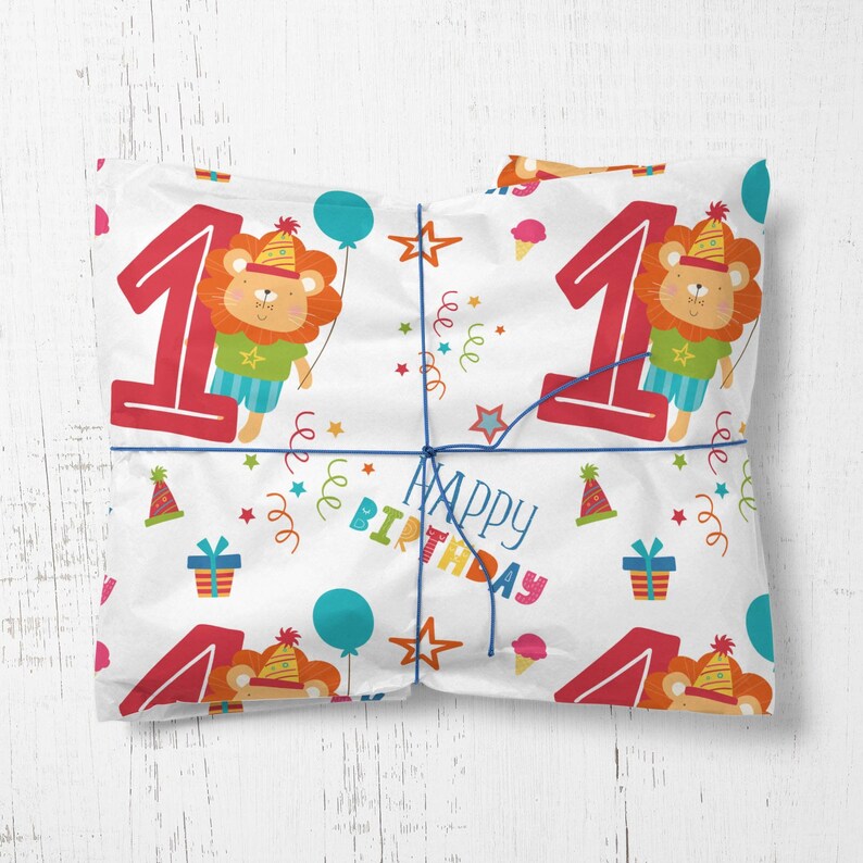 May include: White wrapping paper with a repeating pattern of colorful confetti, stars, and a lion wearing a party hat. The number "1" is in red with the words "Happy Birthday" in a colorful font.