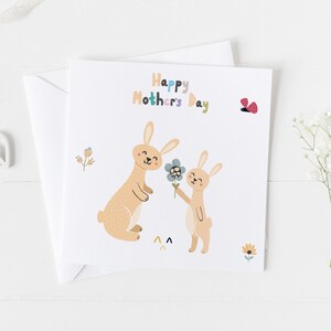 May include: A card with a colorful "Happy Mother's Day" message and two brown bunnies. One bunny is holding a blue flower and the other is smiling. There is a red butterfly in the top right corner.