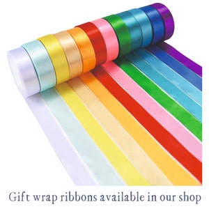 Op de afbeelding: Een selectie van kleurrijke satijnen lintrollen, perfect voor het inpakken van cadeaus. De linten zijn gerangschikt in een regenboogpatroon, met kleuren die vari&euml;ren van paars tot lichtblauw.