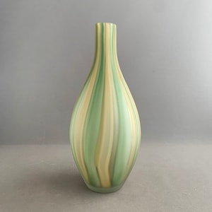Può includere: Un vaso di vetro a righe verdi e gialle con fondo arrotondato e collo stretto.