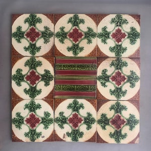 Puede incluir: Nueve baldosas cerámicas cuadradas dispuestas en una cuadrícula. Cada baldosa presenta un círculo color crema con un diseño floral verde y burdeos. La baldosa central tiene un patrón de rayas verdes y burdeos.