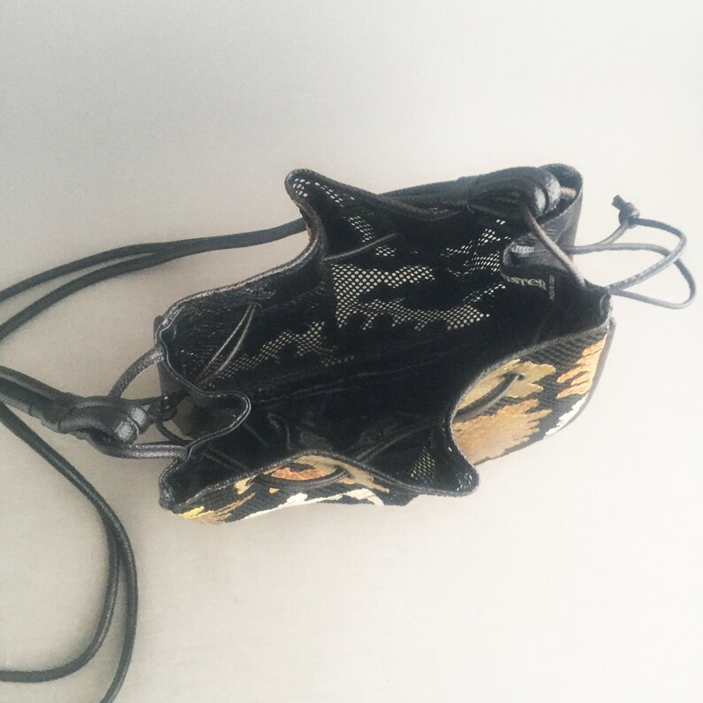 May include: A black drawstring bag with a mesh lining and a tiger print design. The bag has a long black strap.