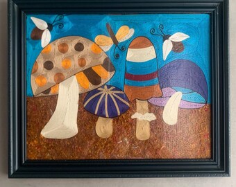 May include: Framed artwork featuring colorful mushrooms and butterflies against a blue background. The mushrooms have various designs and colors, including brown, orange, and purple. The butterflies are white and yellow. The artwork is in a dark blue frame.