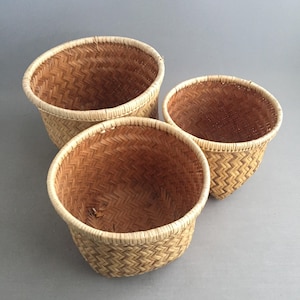 Könnte beinhalten: Drei geflochtene Körbe in verschiedenen Größen. Die Körbe bestehen aus hellbraunem, gewebtem Material mit einem helleren Rand. Die Körbe haben eine runde Form und ein strukturiertes Aussehen. Die Körbe sind leer und scheinen handgefertigt zu sein.