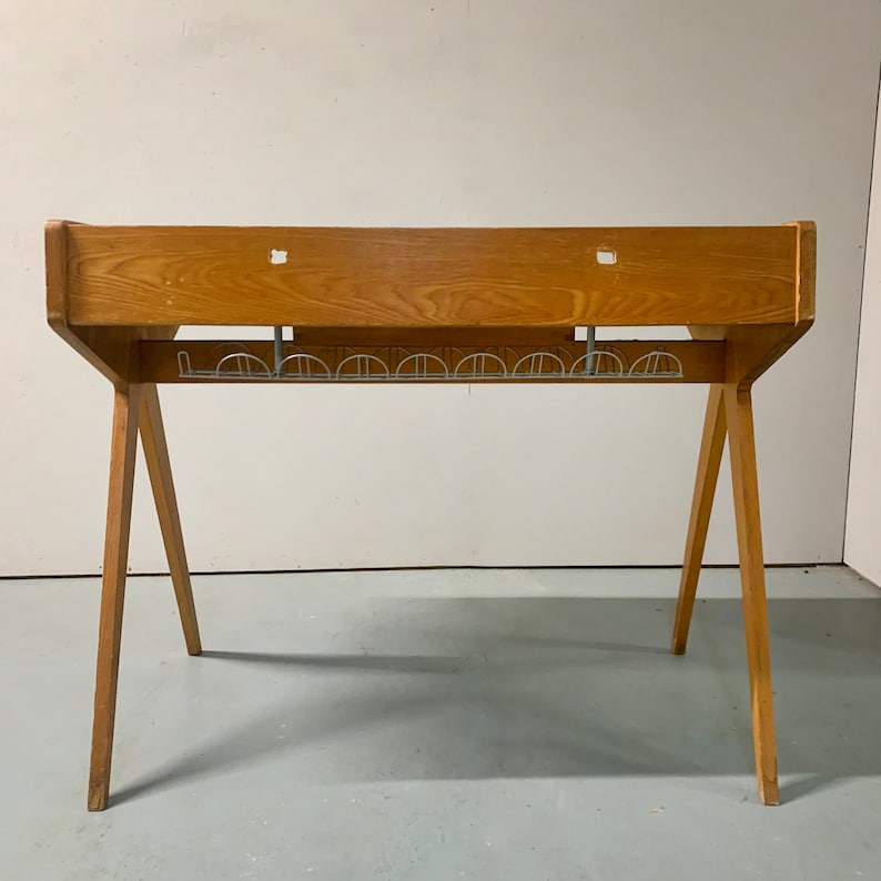 May include: A wooden desk with a metal wire rack underneath. The desk has a simple, minimalist design with a rectangular top and angled legs.