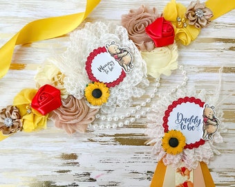 May include: Two Winnie the Pooh themed sashes for a baby shower. The sash on the left says "Mommy to be" and the sash on the right says "Daddy to be". Both sashes feature a Winnie the Pooh character, a sunflower, and a red bow.