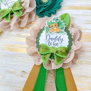 May include: A light brown and green flower with a green bow and a lion character in the centre. The flower has a scalloped edge and a white label that says "Daddy to be".