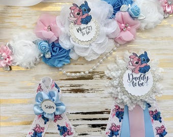 May include: A blue and pink floral sash with a white lace overlay and a pearl string. The sash has a blue and pink Stitch character with the text "Mommy to be" and "Daddy to be". There are also three smaller sashes with a blue and pink Stitch character and the text "Sister".