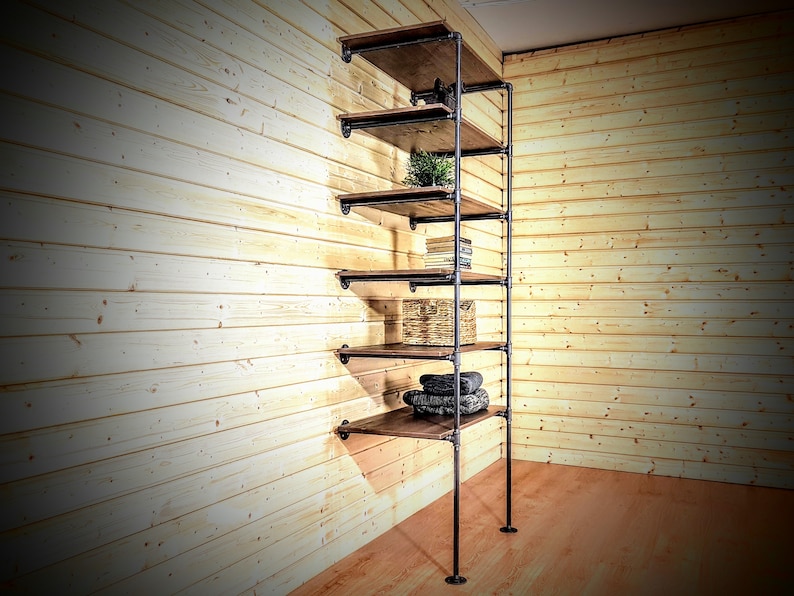 May include: A six-shelf industrial pipe shelving unit with wooden shelves. The shelves are empty except for the third shelf, which has a wicker basket, and the fifth shelf, which has a stack of folded towels.